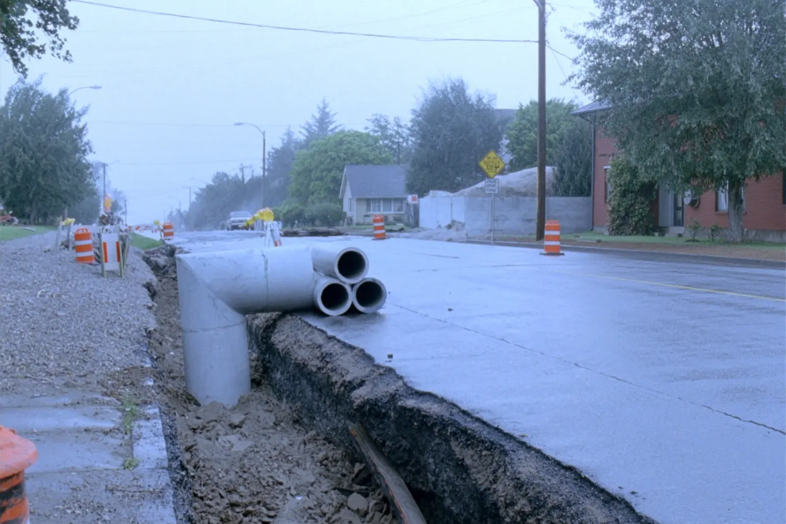 Municipal road reconstruction, with storm sewer pipe sections beside an excavated trench.